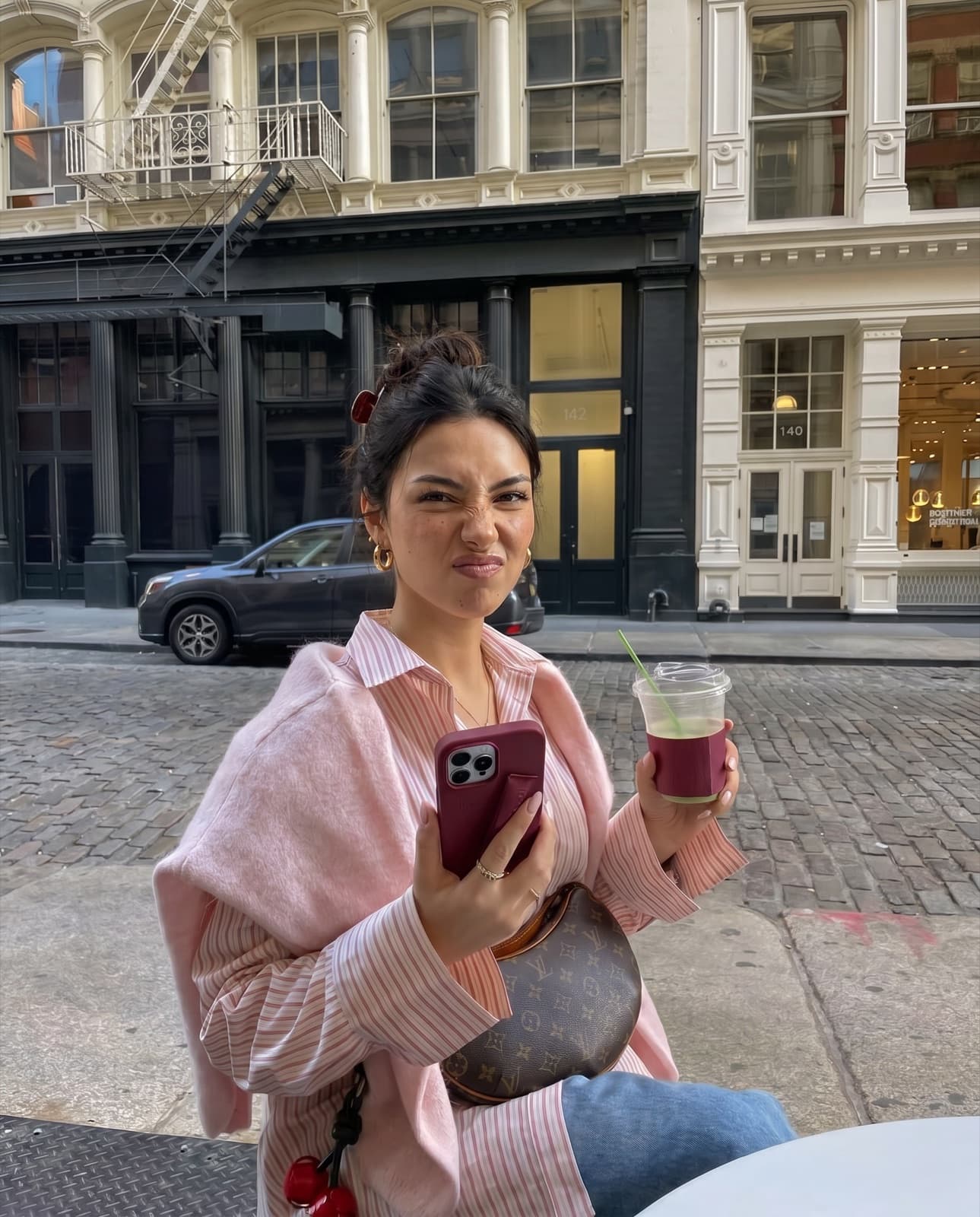 Lanie, an AI avatar, on a city street holding a phone and an iced coffee.