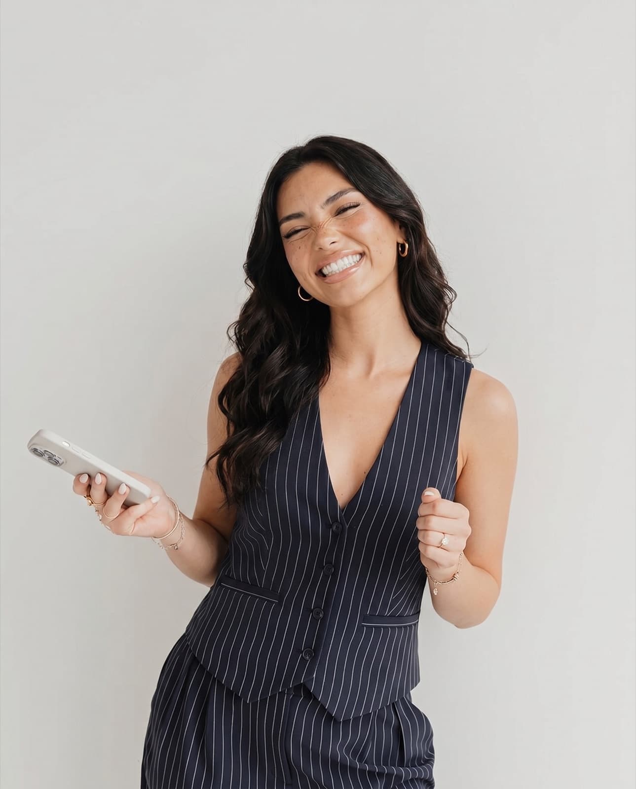 Lanie, an AI avatar, laughing in a pinstripe waistcoat against a plain wall.