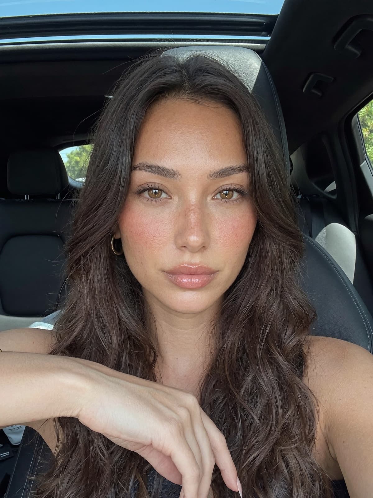 Lanie, an AI avatar, sitting in a parked car.