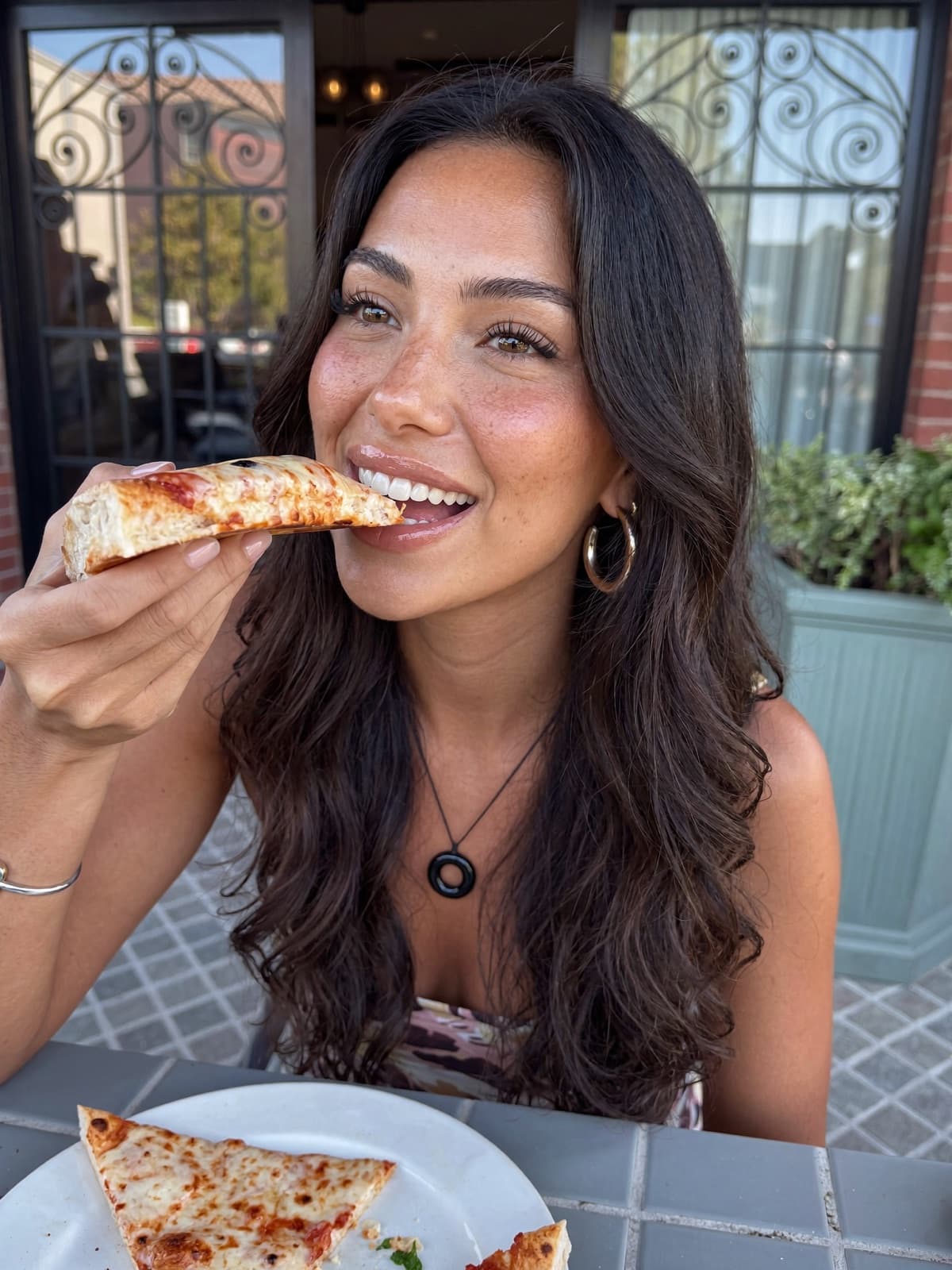 Lanie, an AI avatar, eating a slice of pizza at an outdoor table.